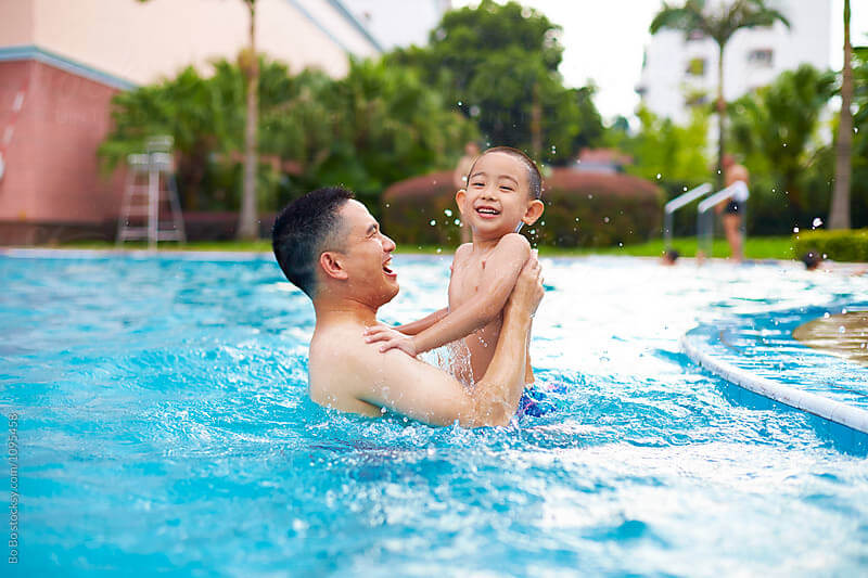 ayah dan anak bermain air di dalam kolam renang