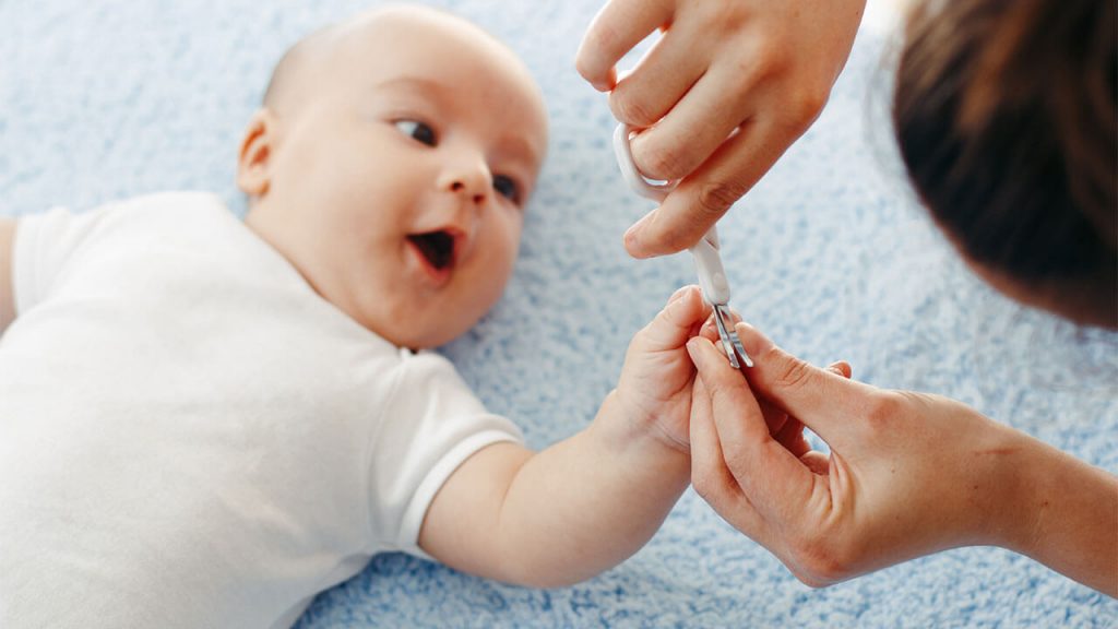 ibu memotong kuku bayi baru lahir di tempat dengan cahaya terang