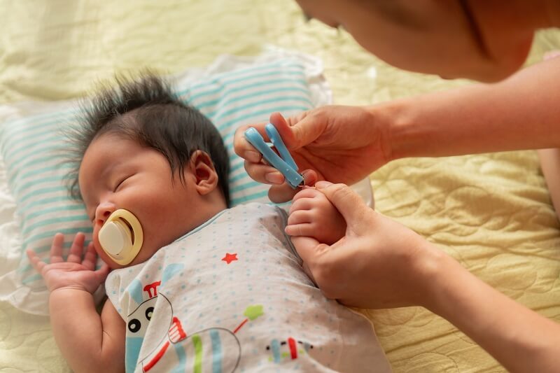 ibu potong kuku bayi baru lahir yang sedang tidur