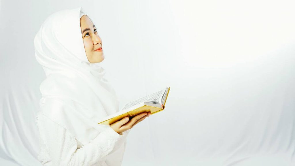 wanita memegang Al-quran dan mengamalkan doa penyeri wajah